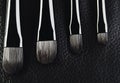 four makeup brushes close-up on a textured black leather background. horizontal Royalty Free Stock Photo