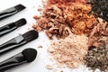 Four makeup brushes and crumbled eyeshadows of different colors