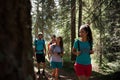 Four man and woman walking along hiking trail path in forest woods during sunny day. Group of friends people summer Royalty Free Stock Photo