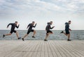 Four men clones running in sports wear along seaside Royalty Free Stock Photo