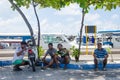 Four men sitting on pavement at docks area