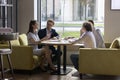 Four millennial businesspeople negotiating in modern office