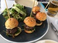 Four mini burger sliders on plate at restaurant