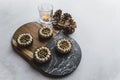 Four mini chocolate dessert tarts served on wooden and stone tray on stone table with candle and decorative pinecones