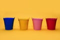 Four multi-colored buckets on a yellow background with place for text