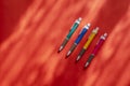 Four multi-colored pens on a red background with shadows Royalty Free Stock Photo