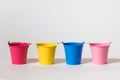 Four multi-colored toy buckets on a white background