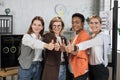 Four multi ethnic female workers showing thumb up and smiling on camera during business meeting Royalty Free Stock Photo