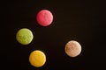 Four multicolored macarons on a black background