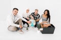 Four multiethnical riends, students, coworkers, holding hands on the globe, looking at camera and smiling, sitting on Royalty Free Stock Photo