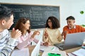 Four multiracial cheerful happy colleagues discussing project in modern office.