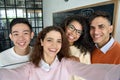 Four multiracial cheerful happy students taking selfie in classroom. Royalty Free Stock Photo