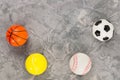 Four new soft rubber basketball and baseball and tennis and soccer balls on old worn cement