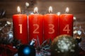 Four numbered red advent candles with first candle lit and christmas decoration lying in snow as template Royalty Free Stock Photo