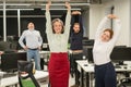 Four office workers warm up during a break. Employees do fitness exercises at the workplace.