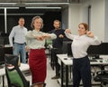 Four office workers warm up during a break. Employees do fitness exercises at the workplace.