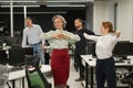 Four office workers warm up during a break. Employees do fitness exercises at the workplace.