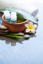 Four oil bottles in bowl of water, towel, flower.