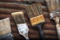 Four Old Crusty Household Paintbrushes Lined at an Angle Rusted Corrugated Metal Background