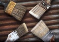 Four Old Dirty Crusty Household Paintbrushes on Rusted Corrugated Metal Background Royalty Free Stock Photo