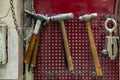 Four old hammers with a brown wooden handle and a clamp hang on the wall in the workshop for carpentry work on a red background Royalty Free Stock Photo