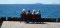 Four older ladies sitting on bench looking at view across sea