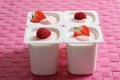 Four open yoghurt cups with fruits