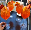 Four orange cocktails in glasses with hand with fruits