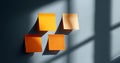 Four orange sticky notes arranged on a gray wall with dramatic shadows cast by window light creating geometric patterns Royalty Free Stock Photo