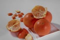 Four oranges lie on a white ceramic plate and one is broken in half with a peeled peel on a white background Royalty Free Stock Photo