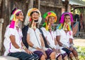 Four Padaung women in traditional dress and with metal rings around their neck are sitting next to each other in the village