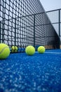 four paddle tennis balls next to the net on a blue artificial grass court Royalty Free Stock Photo