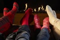 Four pairs feet in socks warming by fire