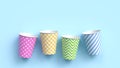 Four paper cups with different colorful patterns on blue pastel background