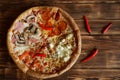 Four-part assorted pizza and red chilli peppers on natural pine plank wood surface. Food for gourmets