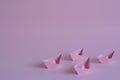 Four pastel pink paper boats on a light pink background.