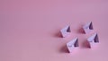 Four pastel purple paper boats on a light pink background.