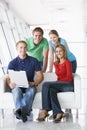 Four people in lobby with laptop smiling