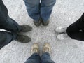Four people stand in different shoes on the white surface of the earth