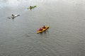 Four people on three kayaks are floating on a calm river. Several people are paddling a kayak. Kayaking on the river