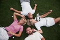 Four people, two guys and two girls, lie on the golf course and relax after the game