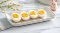 Four perfectly halved boiled eggs on a white ceramic tray in a bright setting Royalty Free Stock Photo
