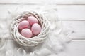 Four pink Easter eggs in the white nest and feathers