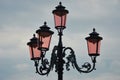 Four pink lamps on an ornate metal stand in Venice