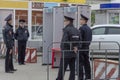 Four policemen in uniform are standing near the frames of a metal detector at a holiday, protecting public order. Side view.