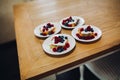 Four portion of sweet bake with raspberry, blueberry and cream on wooden table.