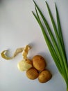 Four potatoes, one half peeled with freshly cut green onion. Vertical photo Royalty Free Stock Photo