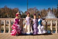 four pretty little girls dancing flamenco dressed in typical gypsy costume pose in a famous square in seville, spain. In the