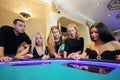 Four pretty women and man play poker in casino