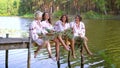 Pretty women in ethnic dresses with floral circlets sitting on wooden bridge